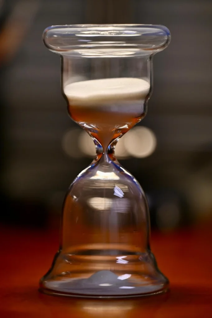 Reloj de arena blanca de cristal sobre mesa de madera. Símbolo de precisión, tiempo y compromiso en Bosch Torreblanca.